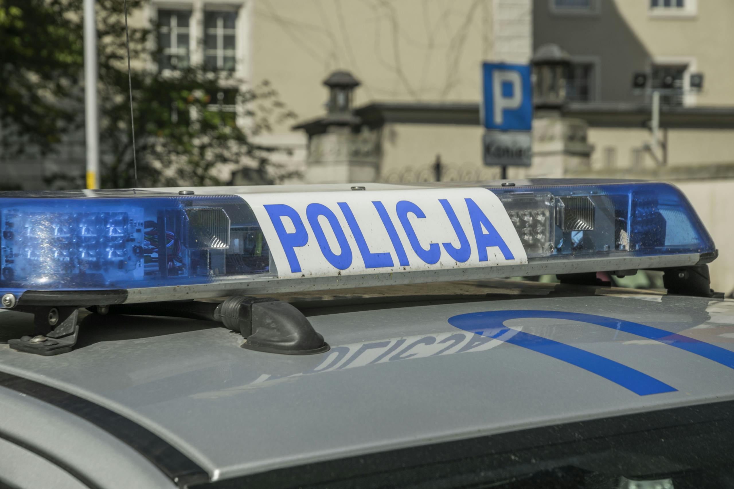 A close-up image showing the light bar of a Polish police car with the word 'Policja'.